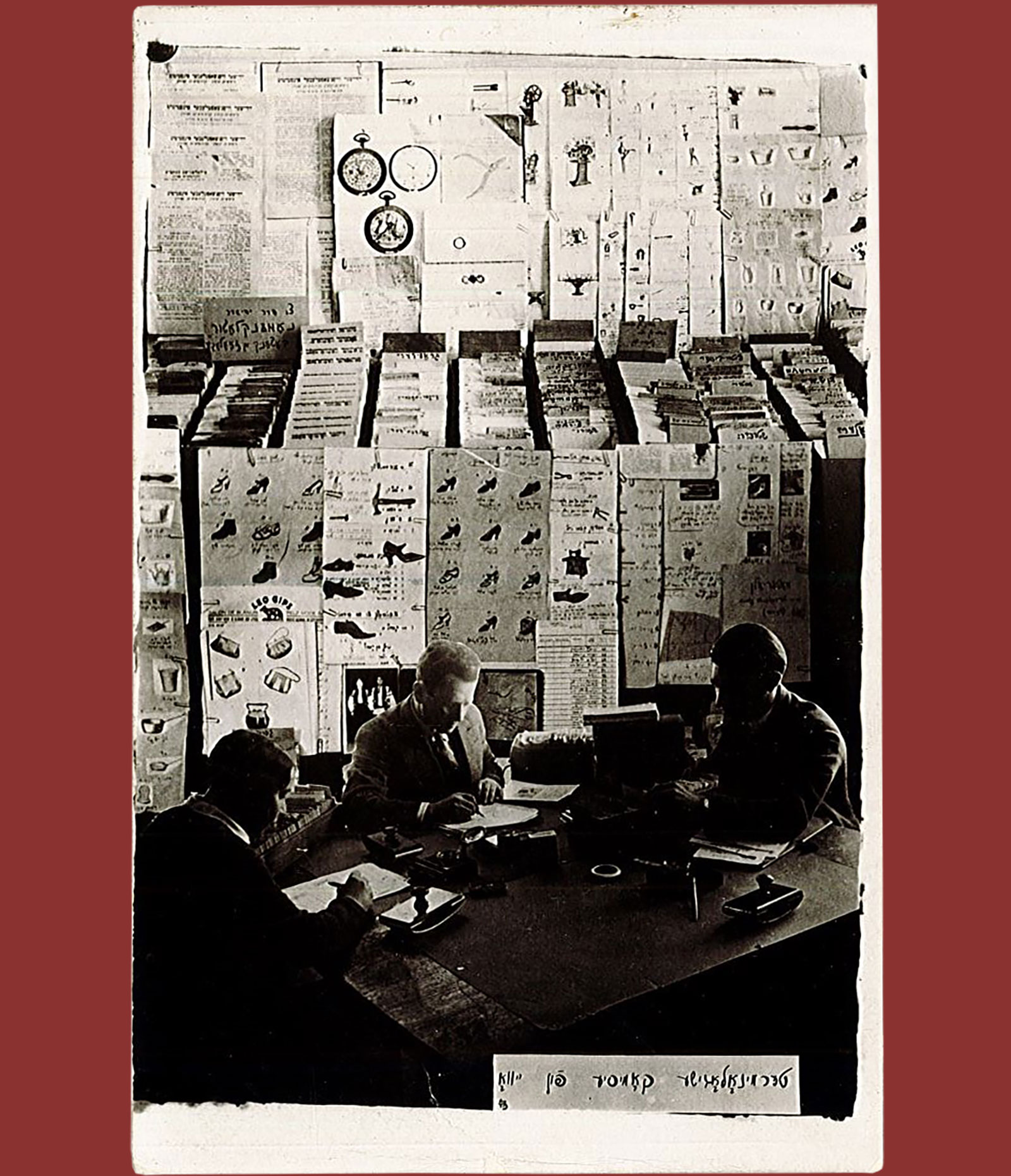 Two students, one from the Real Gymnasium and the other from M'fitsey Haskole, surrounded by charts related 
                            to their YIVO project on Yiddish terminology.  (Center: charts with words related to shoes.)
