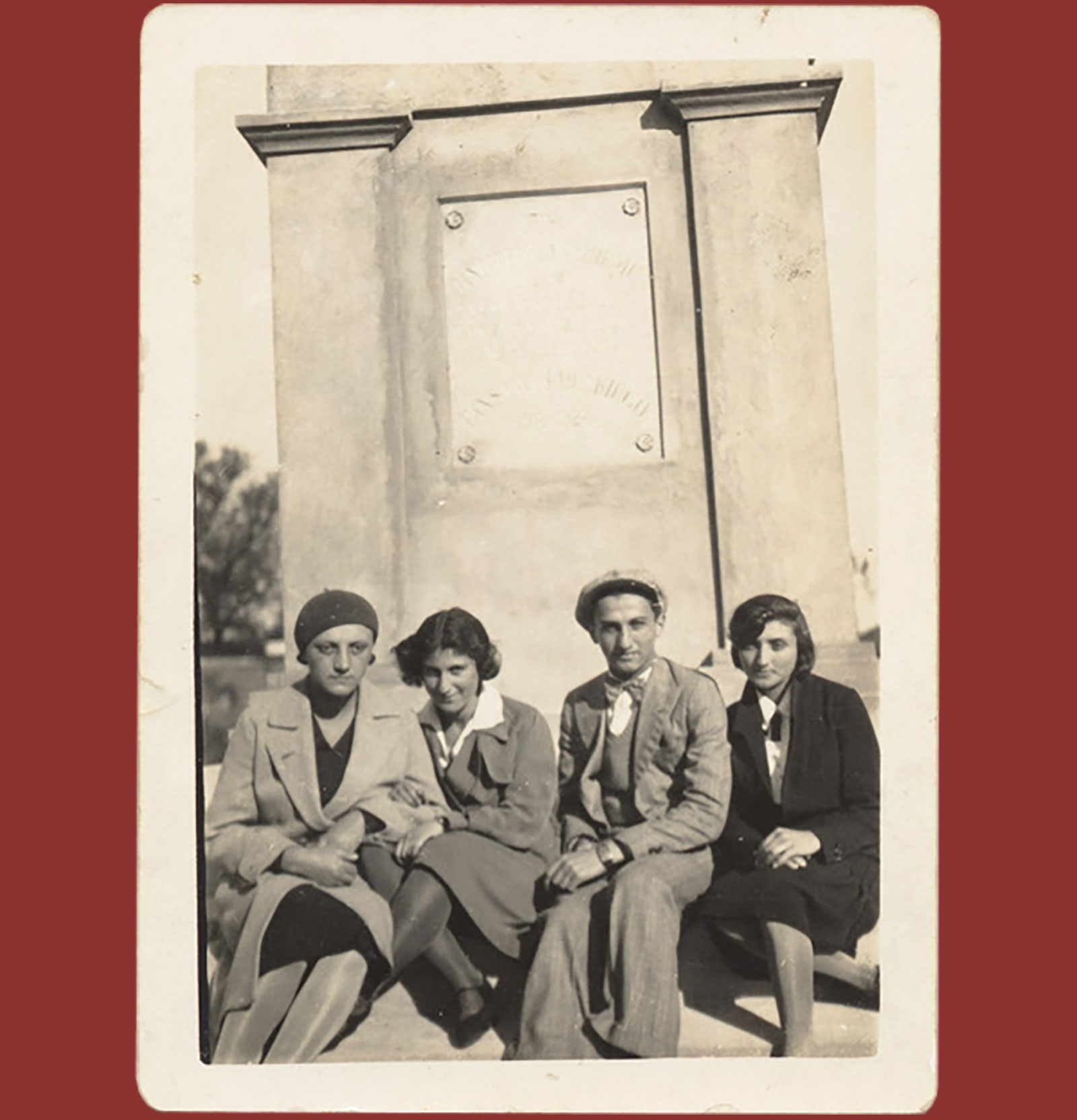 Two men and two women sitting together in front of a grave.