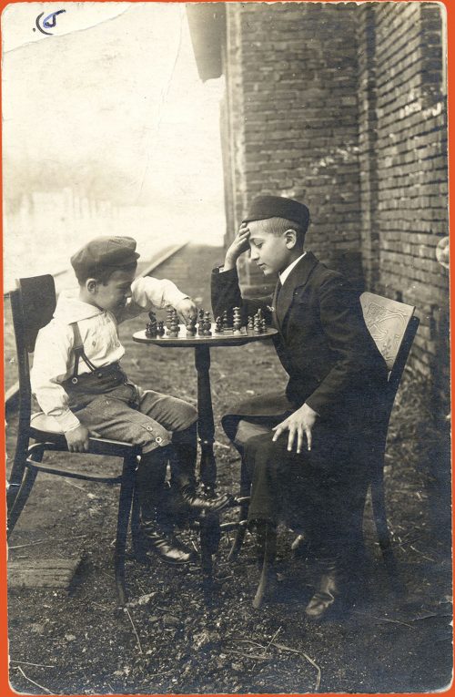 The boys sitting at a table and playing chess