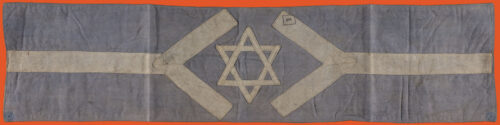 Armband with a light blue background and a horizontal white line crossing it. At the center the horizontal line opens up in two diagonal lines and a white star of david is at the center