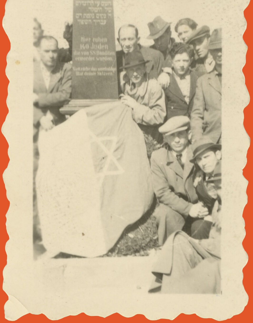 Black and white photo of a group of people around a monument with a flag on top of it.